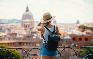Young attractive smiling girl tourist exploring new city at summer