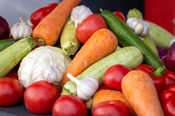 Fresh vegetables are piled up. Tomatoes, cucumbers, carrots, garlic, cabbage, red peppers and zucchini. Preparing to cook food. Lifestyle photo
