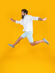 image of happy bearded guy in a hurry wearing summer fashion isolated on yellow background