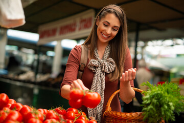 Young woman buying tomatoes in farmers market stall
