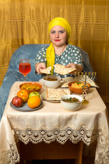 At the festive table on Shabbat, a Jewish woman in a Kisui Rosh headdress breaks matzah.