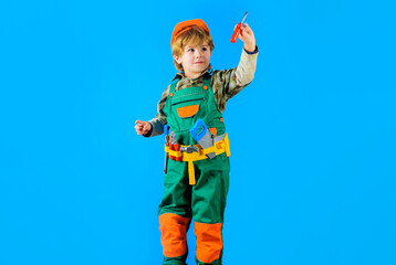 Obraz na płótnie Canvas Child in helmet and toolbelt with screwdriver. Little repairman or craftsman with tools for building. Kid in builder uniform play with toy tools. Little builder, construction worker with repair tool.