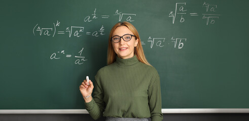 Mature maths teacher near blackboard in classroom