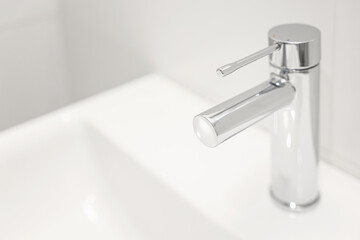 Silver tap of modern sink in bathroom, closeup
