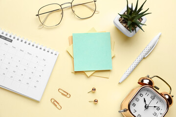 Sticky notes with stationery, calendar, alarm clock and eyeglasses on beige background. Update concept