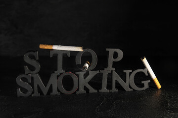 Text STOP SMOKING and cigarettes on dark background