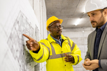 Construction worker and structural engineer discussing about new phase of building project.