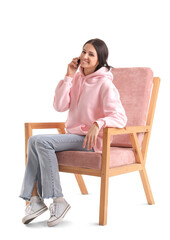 Beautiful woman talking by mobile phone in pink armchair on white background