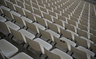 Weiße Stühle in Stadion auf den billigen Plätzen
