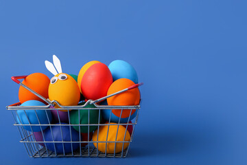 Shopping basket with Easter eggs on blue background