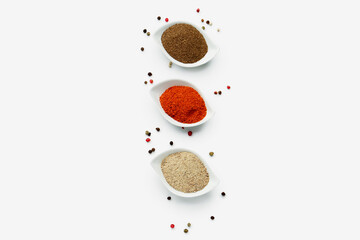 Bowls of spices and peppercorns on light background