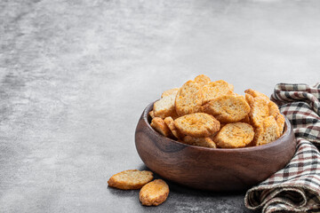 Crispy croutons in wooden bowl on gray background