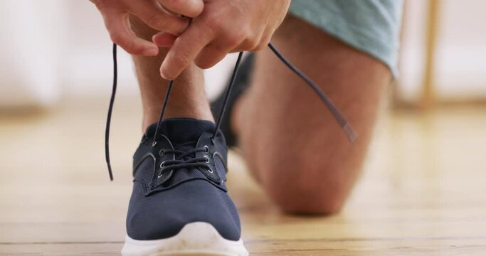 Fitness, getting ready and a man tying his shoes for a cardio or endurance workout as a runner in the home. Running, exercise and training with a male athlete in a house to tie hs laces for sports