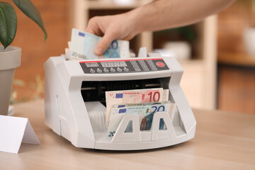Male cashier using cash counting machine in flower shop, closeup