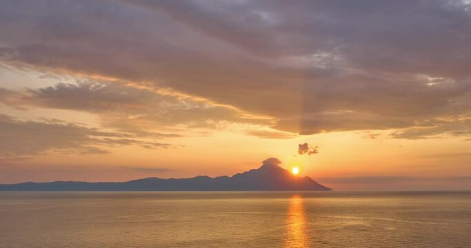 Hyperlapse footage of sunrise over Mount Athos, Athos peninsula, Halkidiki, Greece.  Attractive view of backlit clouds, pinkish purple colors, changing colors.  