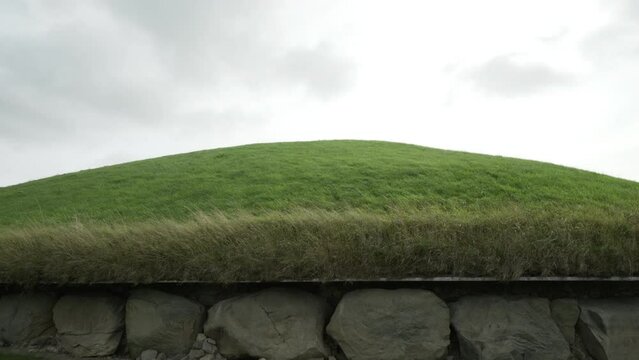 Wind blowing grass on Irish stone age tomb