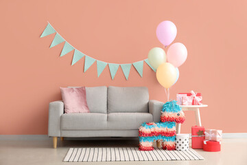 Interior of living room decorated for birthday with balloons, pinata and garland