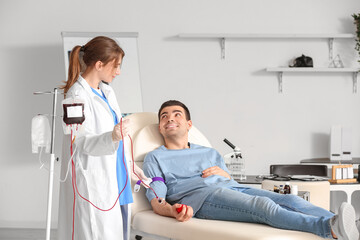 Female doctor taking blood from young donor in clinic
