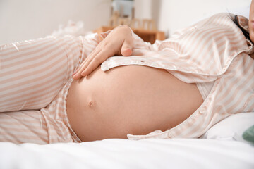 Obraz na płótnie Canvas Young pregnant woman lying in bedroom, closeup