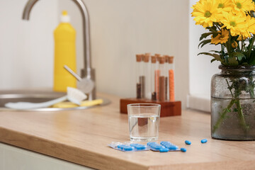 Folic Acid pills and glass of water on counter in kitchen, closeup