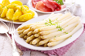 Traditional German white asparagus with boiled potatoes  and serrano ham served as close-up on a design plate