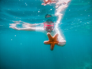 snorkeling woman holding starfish underwater