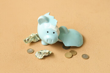 Broken patched piggy bank with money on orange background. Concept of bankruptcy