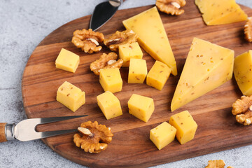 Wooden board with pieces of tasty cheese on table