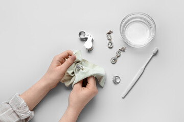 Woman polishing beautiful ring with napkin on white background