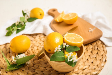 Bowl and board of lemons with blooming branches on white table