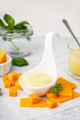 Bowl with tasty cheddar sauce and slices of cheese on grunge table