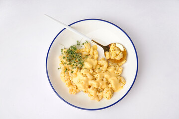 Bowl of tasty Italian pasta with Cheddar cheese on white background