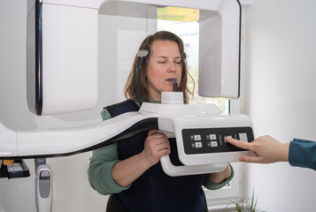 young female patient stand in front of dental X-ray machine, ready to take teeth scanning to diagnose any dental issues. 