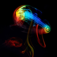 Rainbow colored incense smoke jellyfish like smoke ring under prism light flowing upward colorful smokey scene photographed inside dark studio