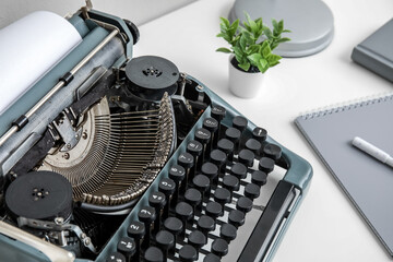 Vintage typewriter with lamp, houseplant and notebook on white background