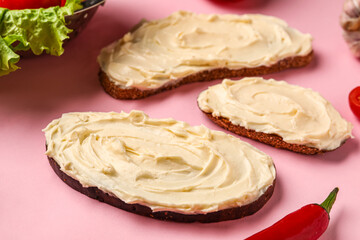 Tasty sandwiches with cream cheese on pink background