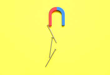 Magnet attracting nails on yellow background