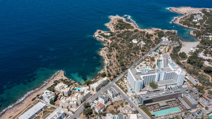 Naklejka premium Aerial drone photo of a beach in the town of Sant Antoni de Portmany on the island of Ibiza Balearic Islands Spain showing the ocean front and Cala Alto de Porta beach in the summer time.