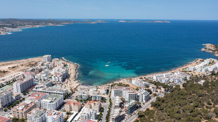 Fototapeta na wymiar Aerial drone photo of a beach in the town of Sant Antoni de Portmany on the island of Ibiza Balearic Islands Spain showing the ocean front and Cala Alto de Porta beach in the summer time.