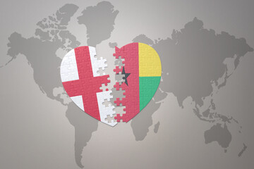 puzzle heart with the national flag of guinea bissau and england on a world map background.Concept.