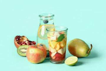 Glass and bottle of infused water with different sliced fruits on blue background