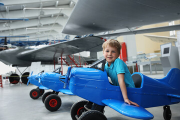 Portrait of cute little blond happy kid boy enjoy have fun play riding pedat toz plane model...