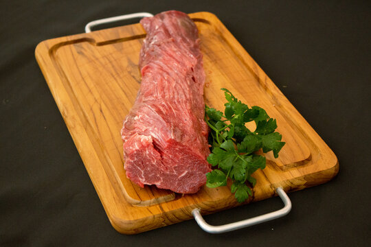 raw filet mignon with green leaves and black background