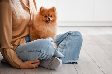 Mature woman with Pomeranian dog in kitchen, closeup