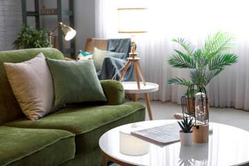 Glowing lamp with succulent and magazine on table in living room