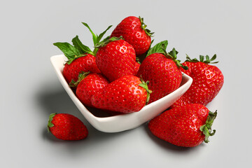 Bowl with fresh strawberries and mint on grey background