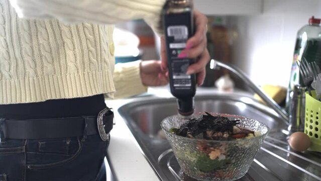 Video of a young woman dressing a nori seaweed and vegetable salad with modena vinegar.