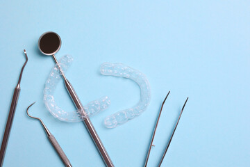 Transparent plastic aligners and dentist's tools on a colored background
