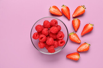 Glass bowl with fresh raspberries and slices of strawberries on lilac background