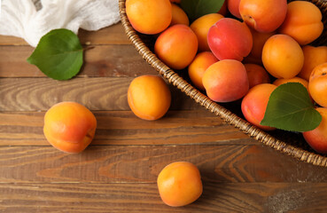 Wicker bowl with fresh apricots on wooden background